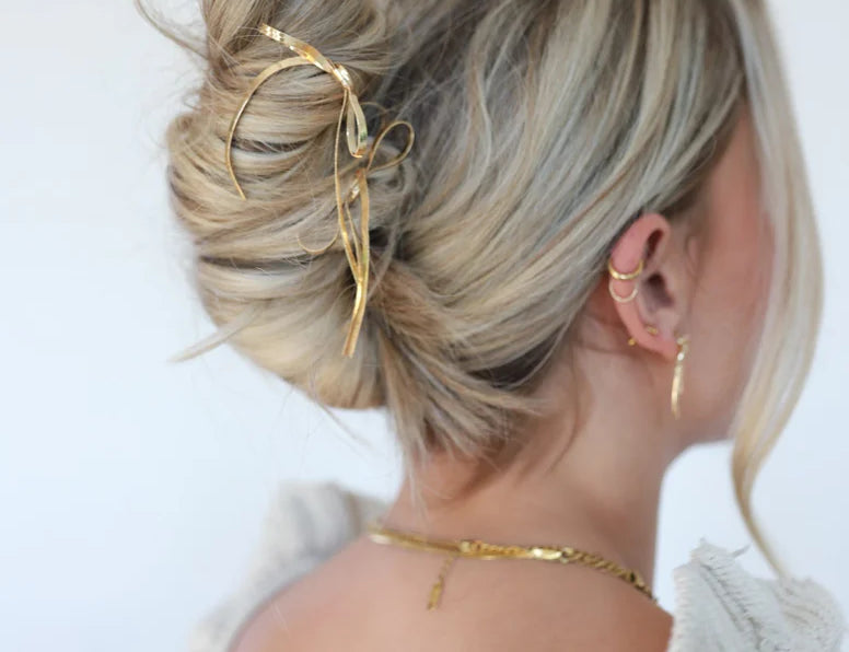 Kaxi Bow Pin in gold holding a loose blonde updo, back view