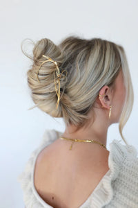 Kaxi Bow Pin in gold holding a loose blonde updo, back view