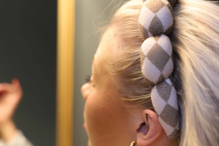Close-up of the braided checkered Kaxi GRWM Headband in Beige worn in blonde hair
