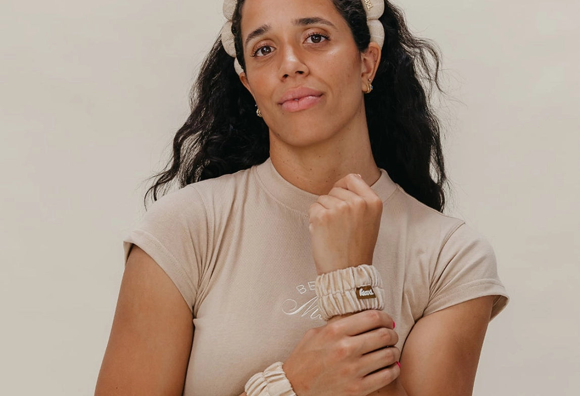 Woman in a beige tee wearing the Kaxi GRWM Headband and Wristbands in Beige, front view