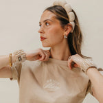 Woman in a beige tee wearing the Kaxi GRWM Headband and Wristbands in Beige, looking to the side