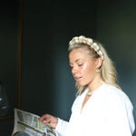Woman in a white blouse reading while wearing the Kaxi GRWM Headband in Beige