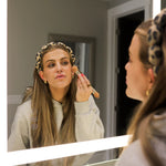 Woman applying makeup in a mirror wearing the Kaxi GRWM Headband in Cheetah