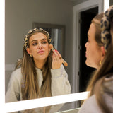 Woman applying makeup in a mirror wearing the Kaxi GRWM Headband in Cheetah