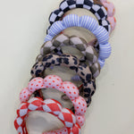 Stack of Kaxi GRWM Headbands in checkered, striped, leopard, floral and red patterns