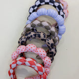 Stack of Kaxi GRWM Headbands in checkered, striped, leopard, floral and red patterns