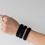Kaxi The Hold All Day Hair Ties in Black worn stacked on a wrist