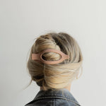 Kaxi Lay Down Claw 2.0 in blush pink holding a French twist, back view