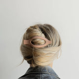 Kaxi Lay Down Claw 2.0 in blush pink holding a French twist, back view
