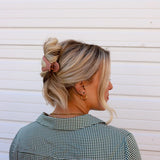 Kaxi Lay Down Claw 2.0 in Champagne holding a loose updo, side back view
