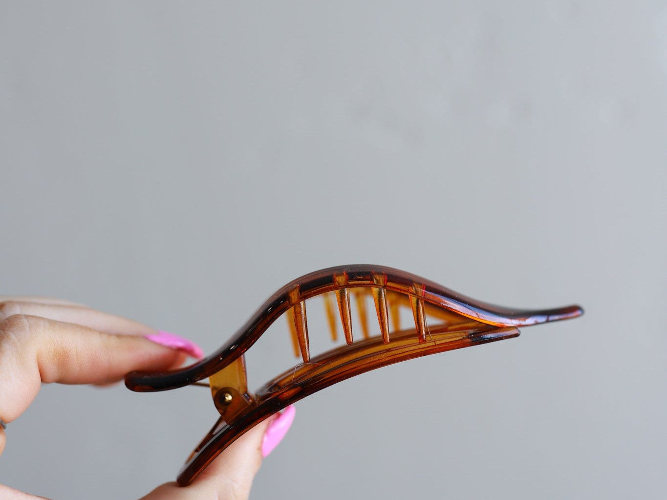 Hand holding the Kaxi Lay Down Claw 2.0 in tortoise, showing its slim curved shape