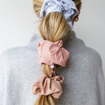 Kaxi Oversized Workout Scrunchies in blush and lavender worn in a ponytail and on the wrist