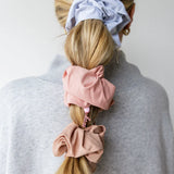 Kaxi Oversized Workout Scrunchies in blush and lavender worn in a ponytail and on the wrist