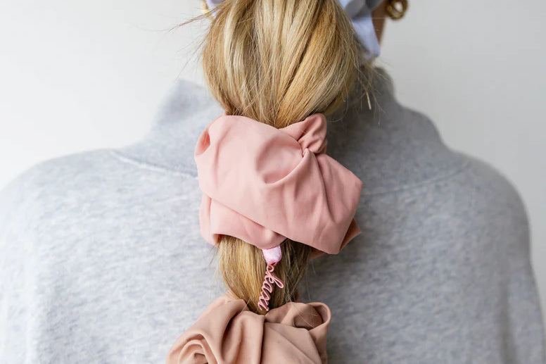 Kaxi Oversized Workout Scrunchies in blush and lavender worn in a ponytail and on the wrist