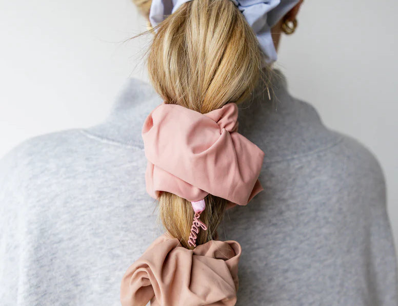 Kaxi Oversized Workout Scrunchies in blush and lavender worn in a ponytail and on the wrist