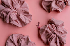 Kaxi Oversized Workout Scrunchies in Blush Pink scattered on a pink background