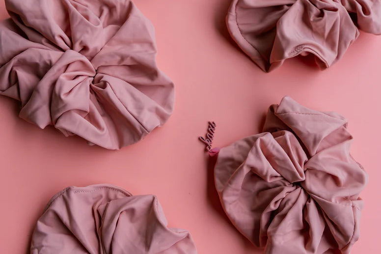 Kaxi Oversized Workout Scrunchies in Blush Pink scattered on a pink background