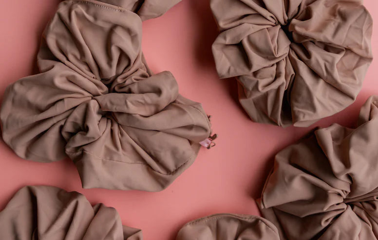 Kaxi Oversized Workout Scrunchies in Nude brown scattered on a pink background