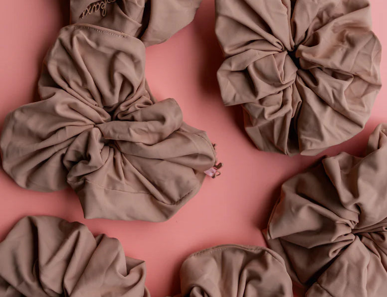 Kaxi Oversized Workout Scrunchies in Nude brown scattered on a pink background