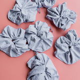 Kaxi Oversized Workout Scrunchies in Soft Blue scattered on a pink background