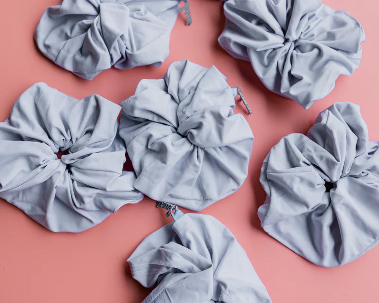 Kaxi Oversized Workout Scrunchies in Soft Blue scattered on a pink background