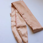 Kaxi Pink Plaid Hair Scarf laid loosely on white showing the gingham print