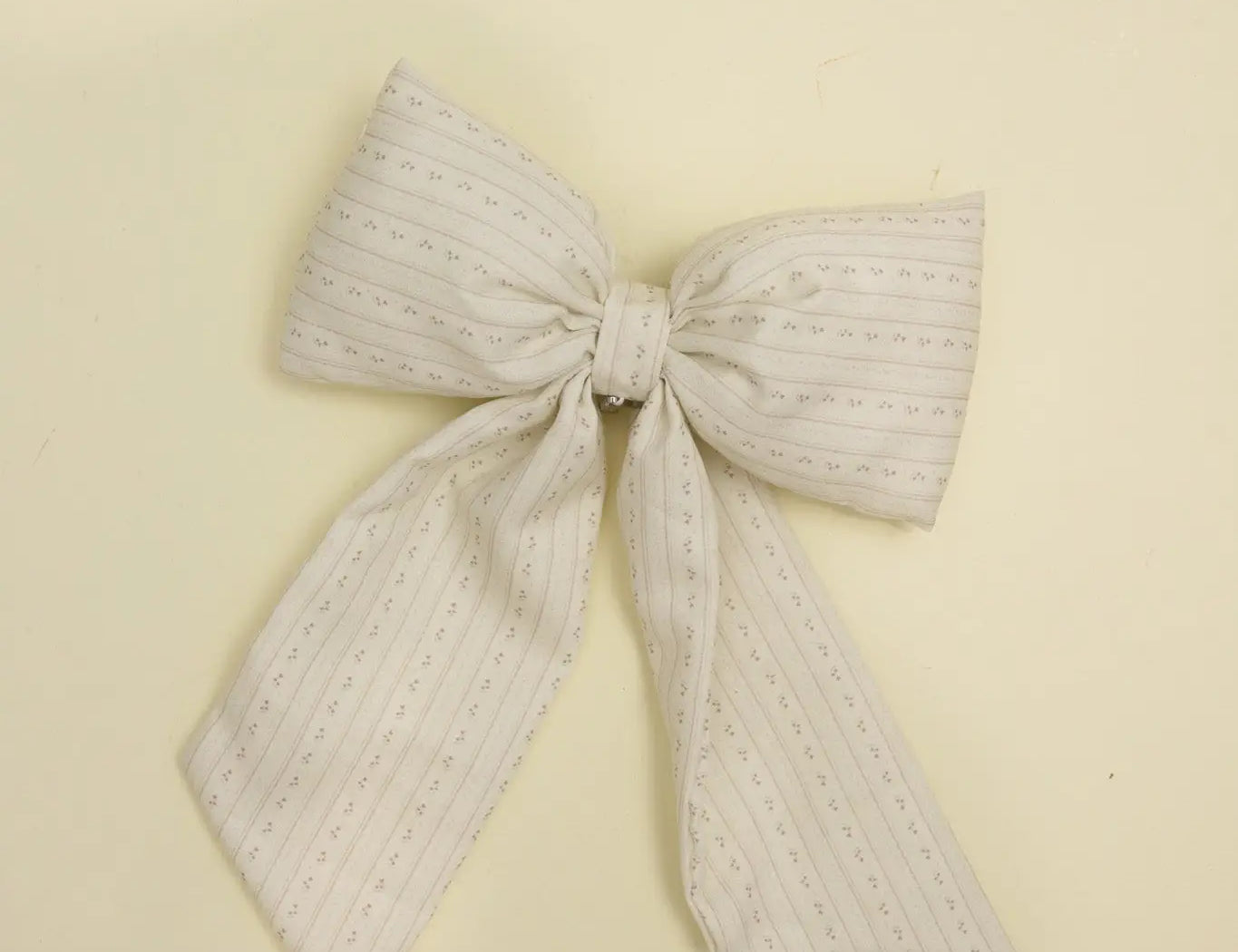 Kaxi Puffy Bow in Blossom, a cream textured fabric bow with long tails, laid flat