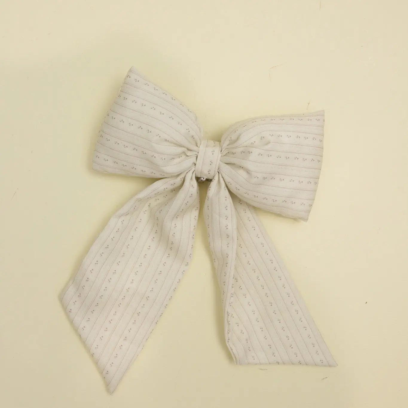 Kaxi Puffy Bow in Blossom, a cream textured fabric bow with long tails, laid flat