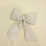 Kaxi Puffy Bow in Blossom, a cream textured fabric bow with long tails, laid flat