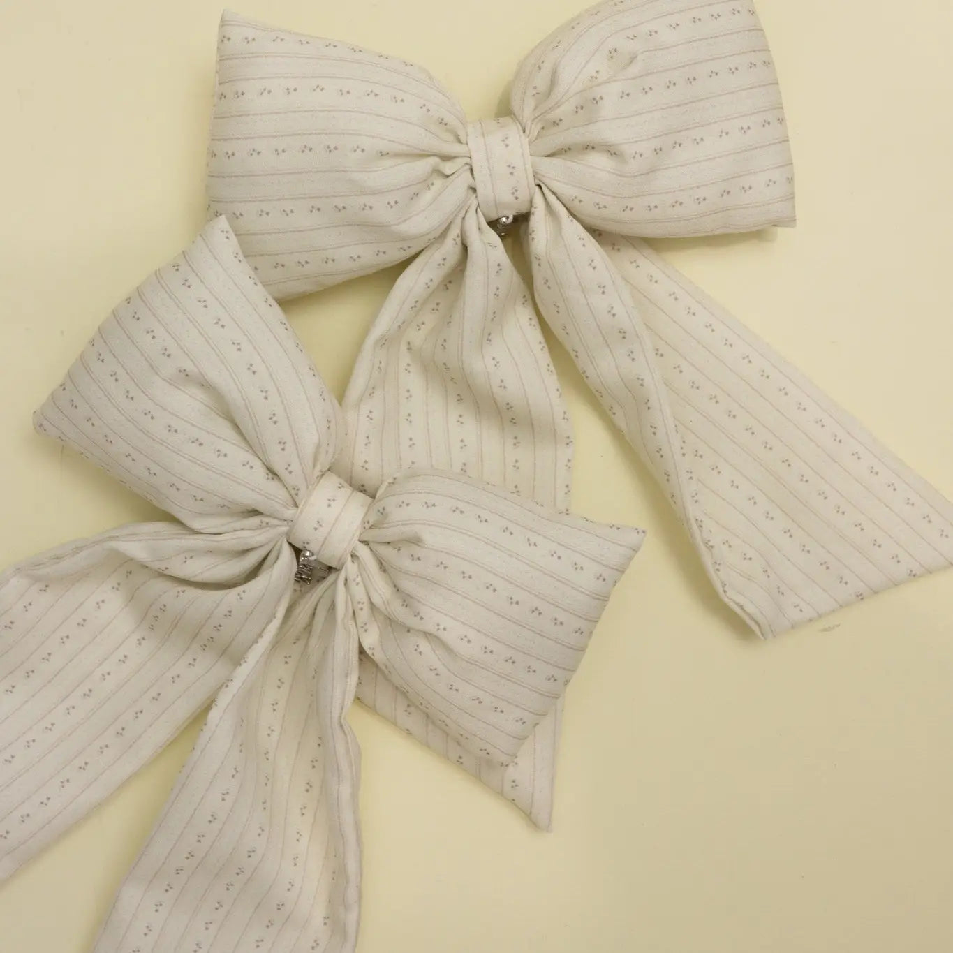 Kaxi Puffy Bows in cream and taupe laid together
