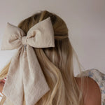 Kaxi Puffy Bow in taupe clipped into a low ponytail, back view