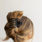 Kaxi Wide Lay Down Claw in black holding a twisted blonde updo, back view