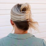 Kaxi Wide Lay Down Claw in clear holding a blonde bun, back view