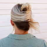 Kaxi Wide Lay Down Claw in clear holding a blonde bun, back view