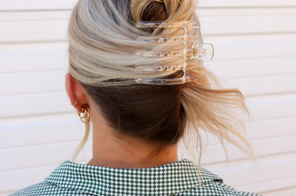 Kaxi Wide Lay Down Claw in clear holding a blonde bun, back view