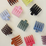 Kaxi Wide Lay Down Claws in assorted colors scattered on white