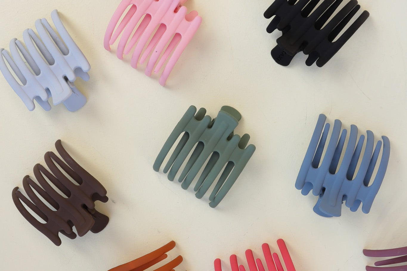 Kaxi Wide Lay Down Claws in assorted colors scattered on white
