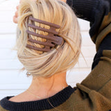 Kaxi Wide Lay Down Claw in taupe holding a blonde French twist, back view