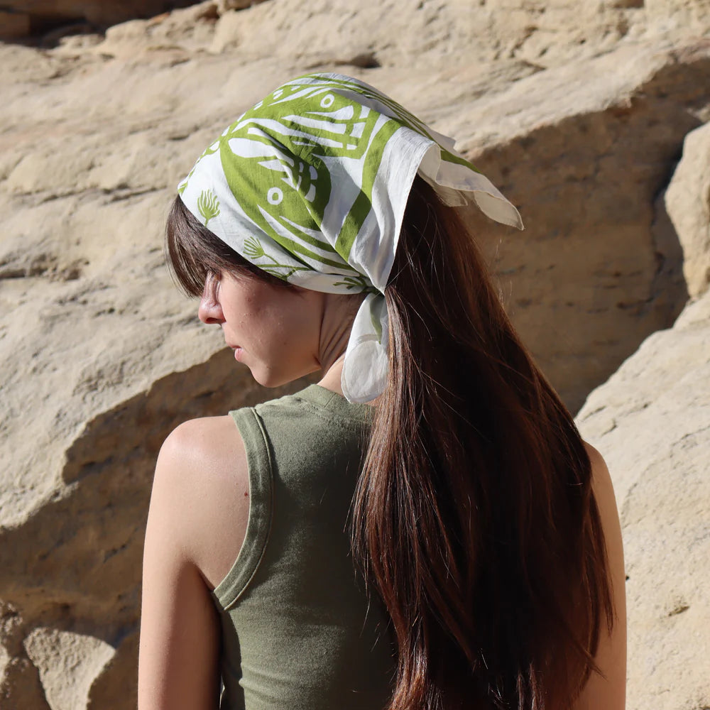 Woman by a rock wall wearing a green and white Kei & Molly Cotton Bandana as a head wrap