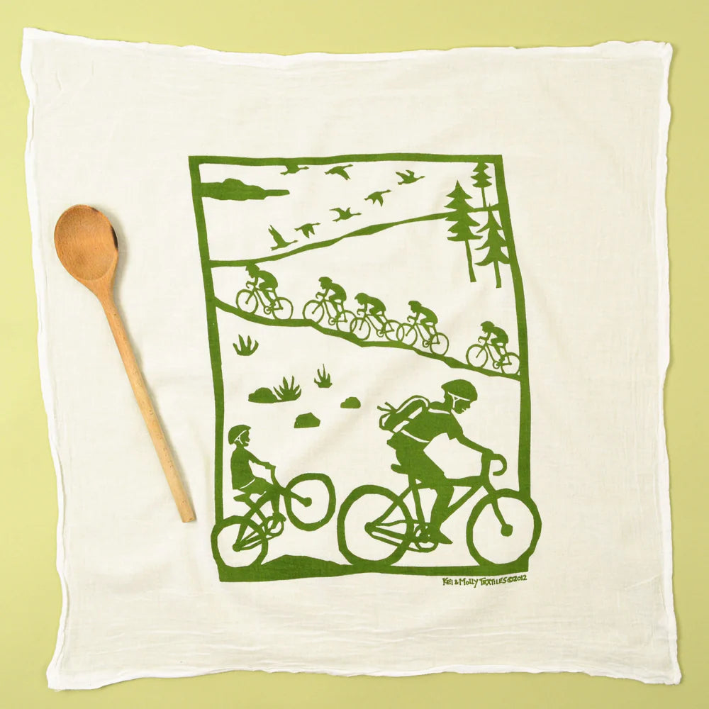 Kei & Molly Flour Sack Dish Towel in Bikes, a white towel with a green print of cyclists on a country road