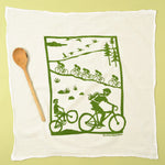 Kei & Molly Flour Sack Dish Towel in Bikes, a white towel with a green print of cyclists on a country road