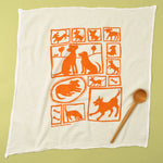 Kei & Molly Flour Sack Dish Towel in Orange Dogs, a white towel with a grid of orange dog illustrations