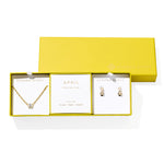 Kendra Scott Cailin Birthstone Gift Set for April in gold with White CZ, a pendant necklace and huggie earrings in a yellow gift box