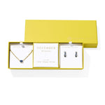 Kendra Scott Cailin Birthstone Gift Set for December in gold with Blue Violet Crystal, a pendant necklace and huggie earrings in a yellow gift box