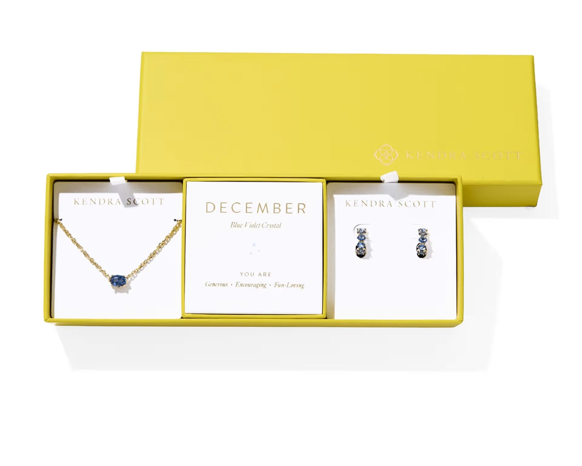 Kendra Scott Cailin Birthstone Gift Set for December in gold with Blue Violet Crystal, a pendant necklace and huggie earrings in a yellow gift box