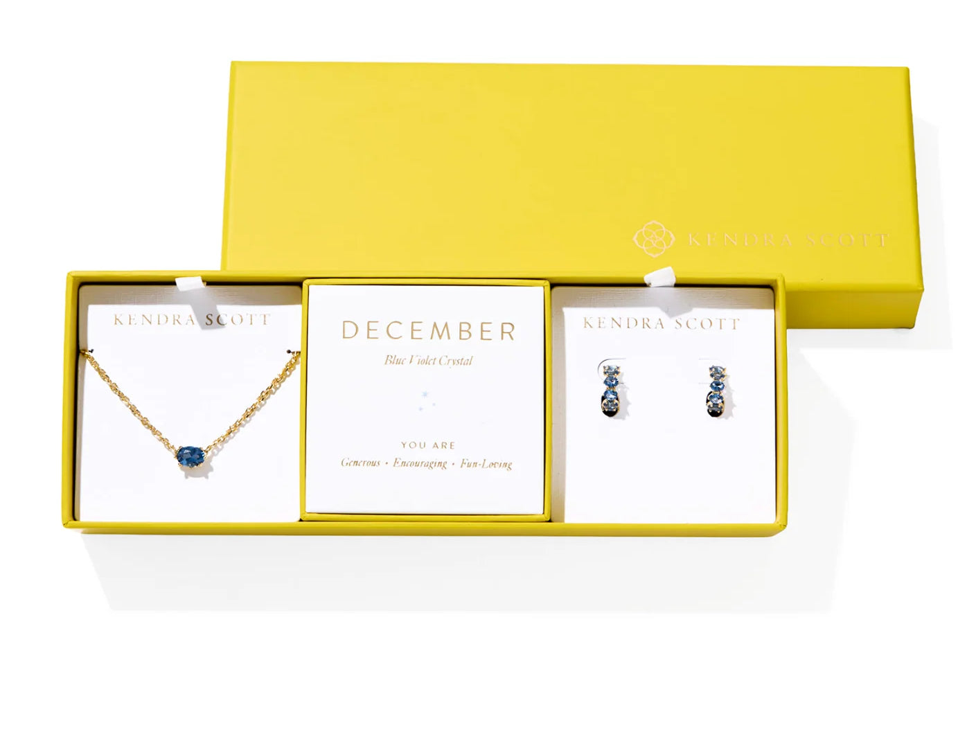 Kendra Scott Cailin Birthstone Gift Set for December in gold with Blue Violet Crystal, a pendant necklace and huggie earrings in a yellow gift box
