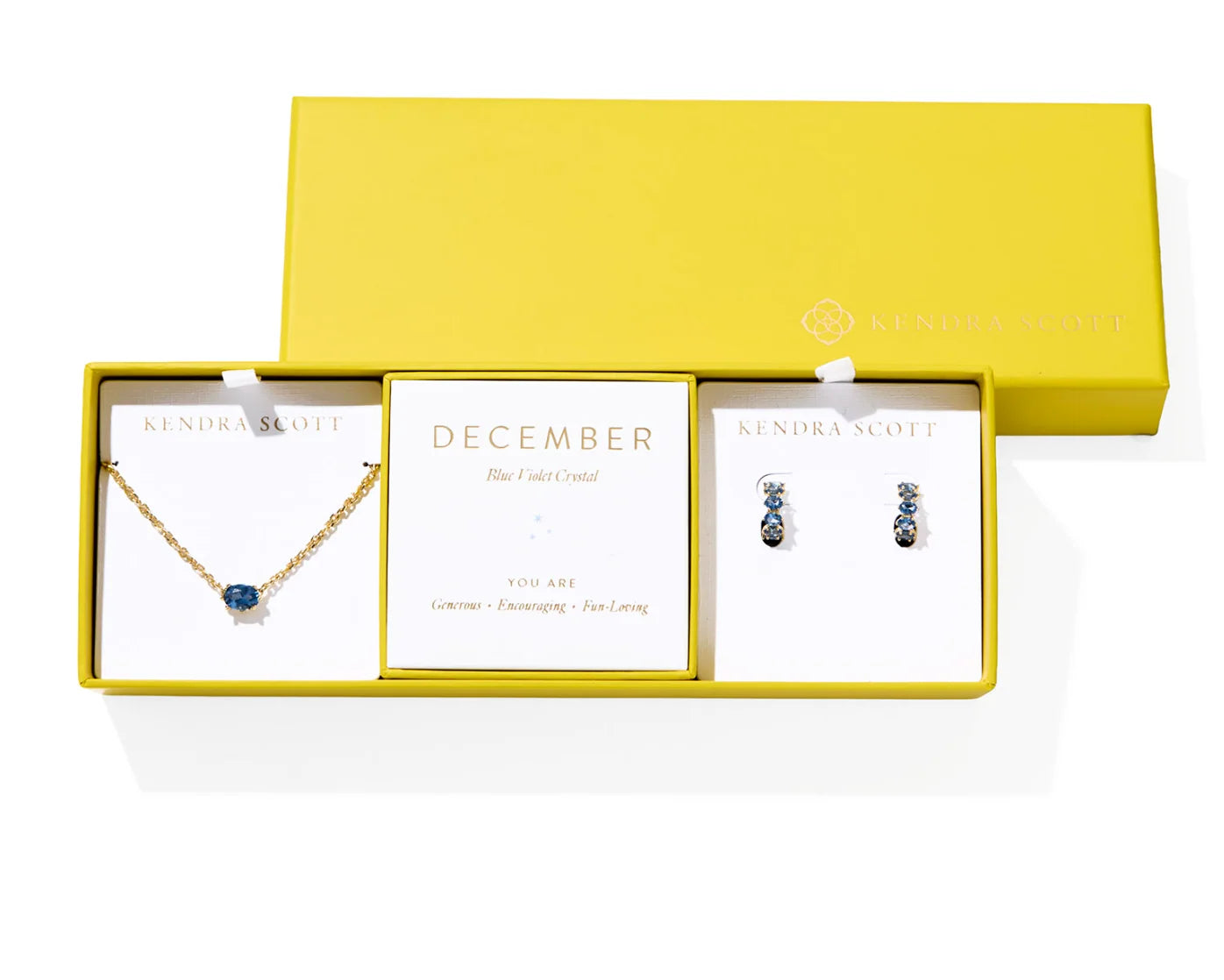 Kendra Scott Cailin Birthstone Gift Set for December in gold with Blue Violet Crystal, a pendant necklace and huggie earrings in a yellow gift box
