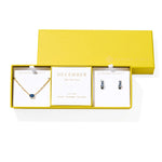 Kendra Scott Cailin Birthstone Gift Set for December in gold with Blue Violet Crystal, a pendant necklace and huggie earrings in a yellow gift box