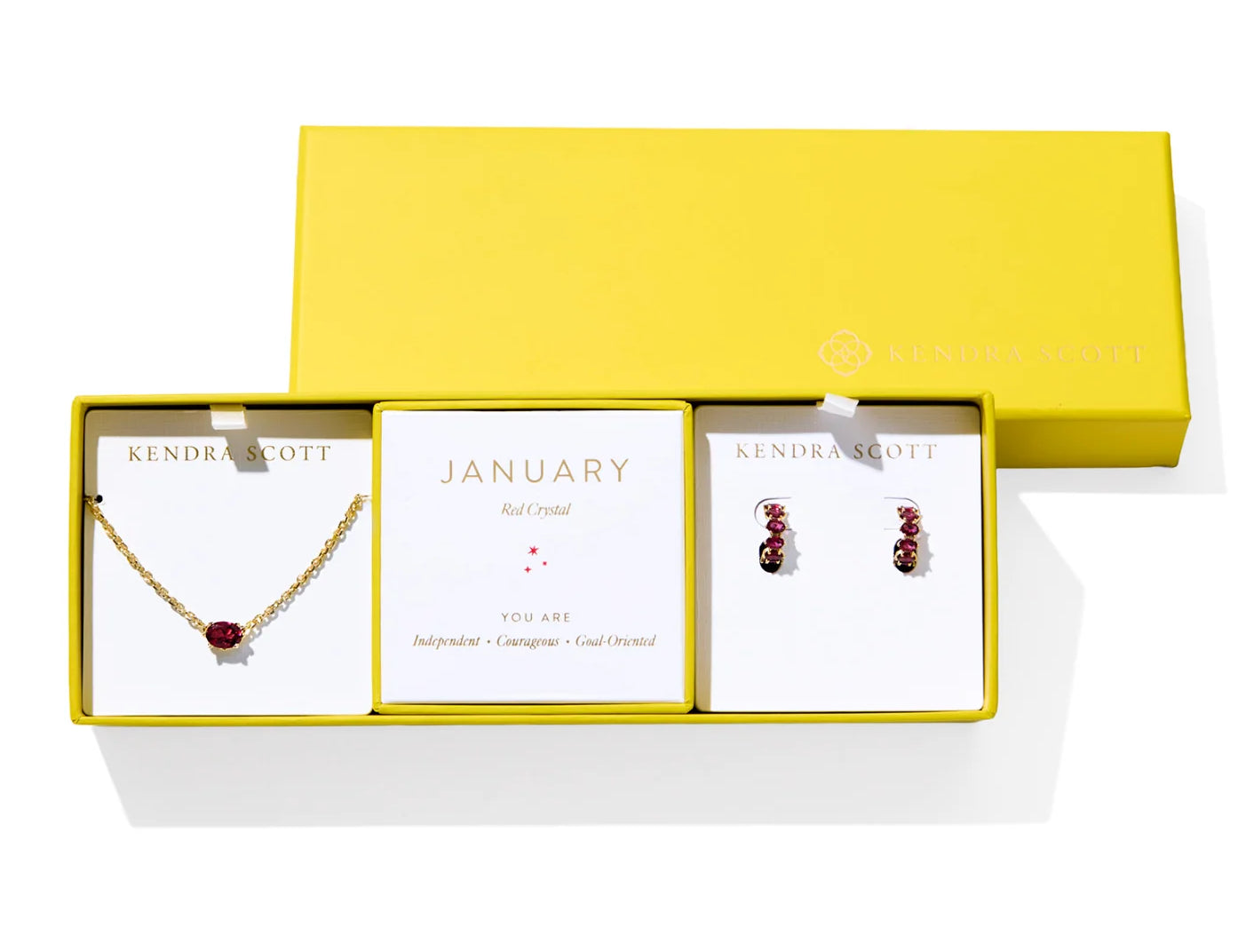 Kendra Scott Cailin Birthstone Gift Set for January in gold with Red Crystal, a pendant necklace and huggie earrings in a yellow gift box