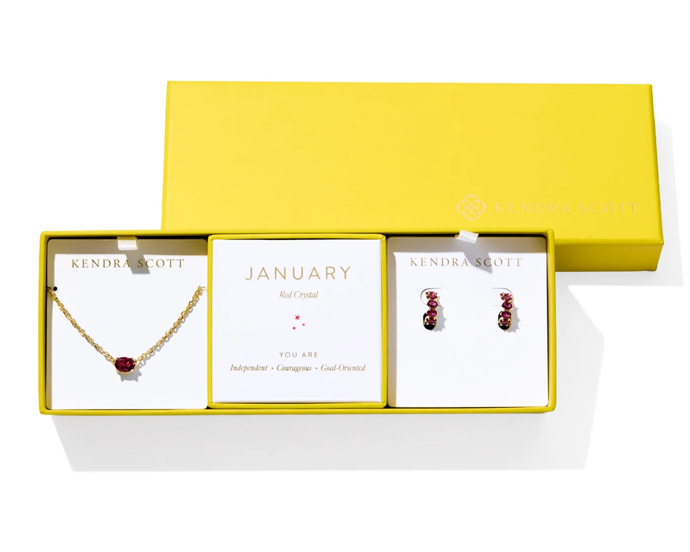 Kendra Scott Cailin Birthstone Gift Set for January in gold with Red Crystal, a pendant necklace and huggie earrings in a yellow gift box